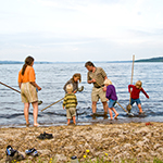 Familie fisker med net på strand